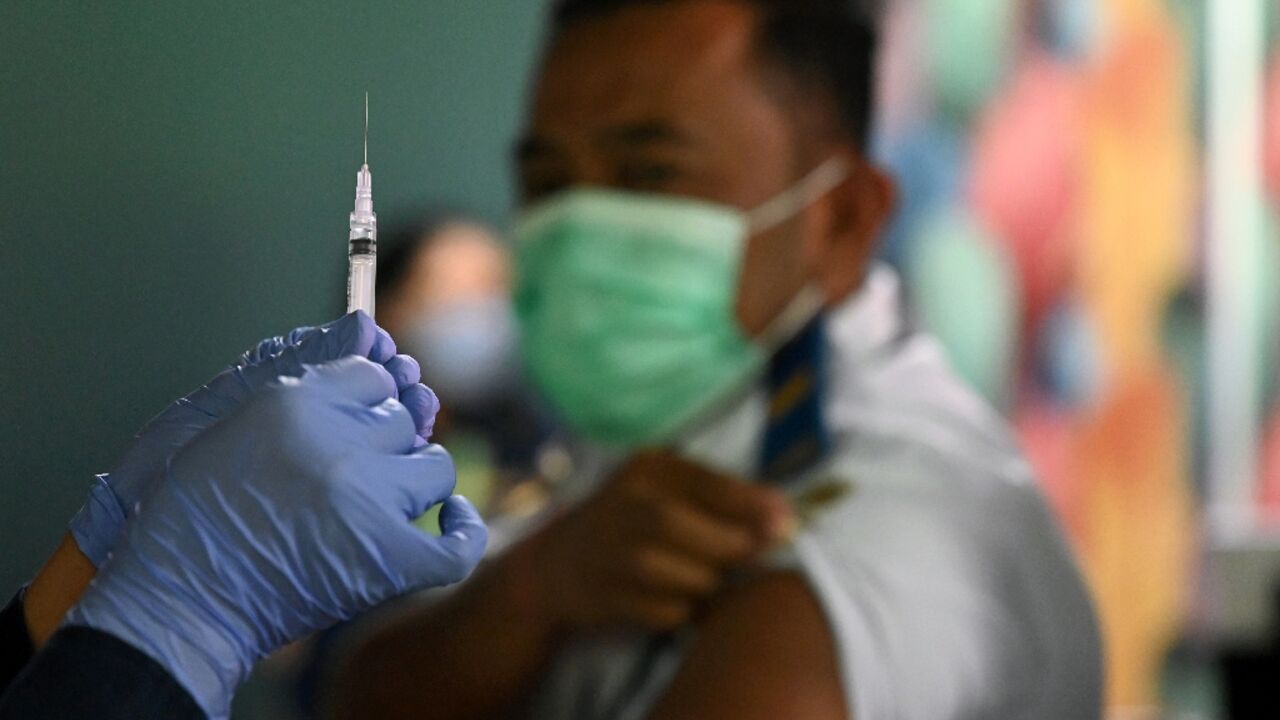 A health worker prepares a Covid booster jab for an airport worker in Bali A health worker prepares a Covid booster jab for an airport worker in Bali