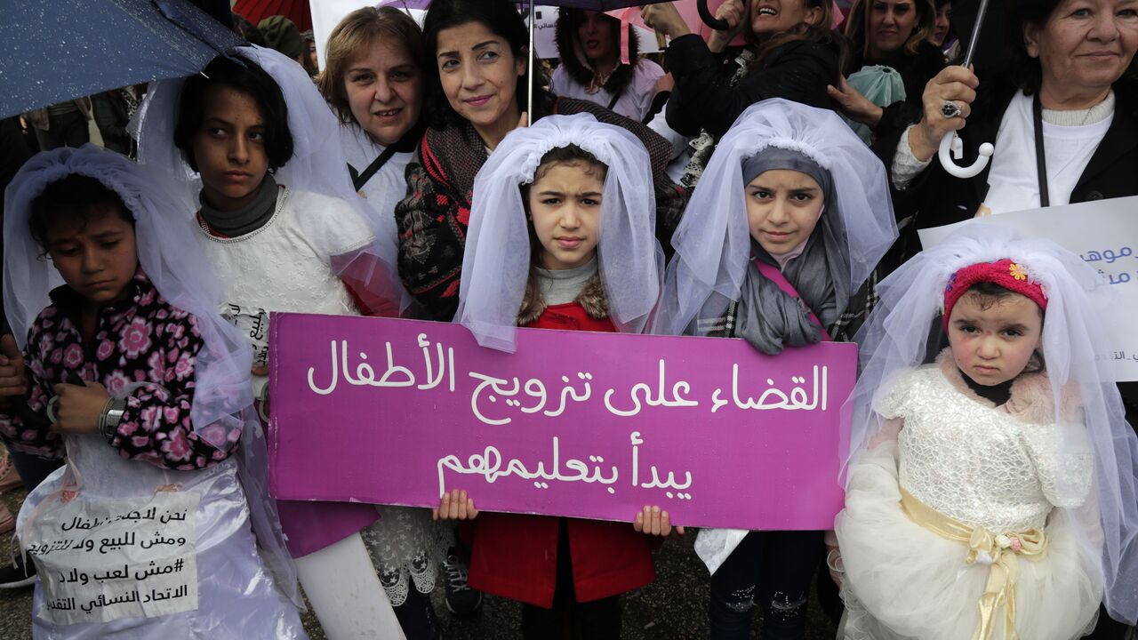 Young Lebanese girls disguised as brides hold a placard as they participate in a march against marriage before the age of 18, in the capital Beirut on March 2, 2019. The placard in Arabic reads "The end of child marriage begins by educating them".  (ANWAR AMRO/AFP via Getty Images)