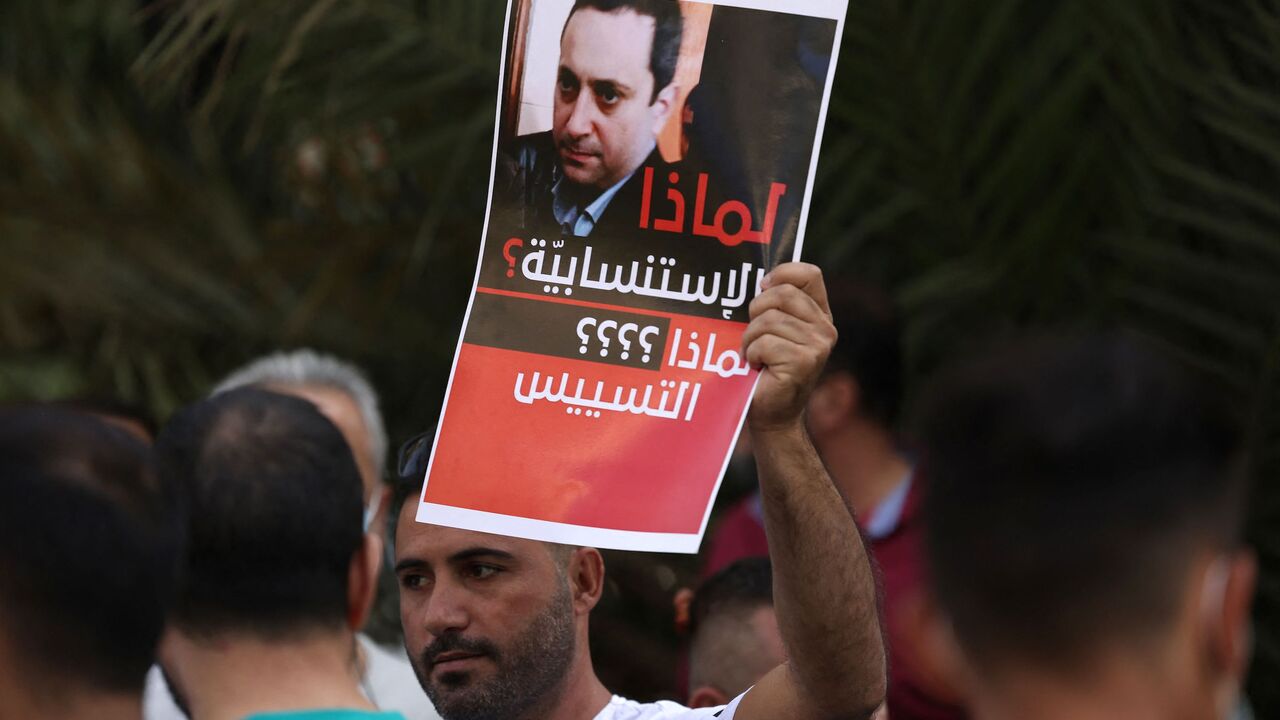 A supporter of Hezbollah and the Amal movements carries a portrait of Judge Tarek Bitar.