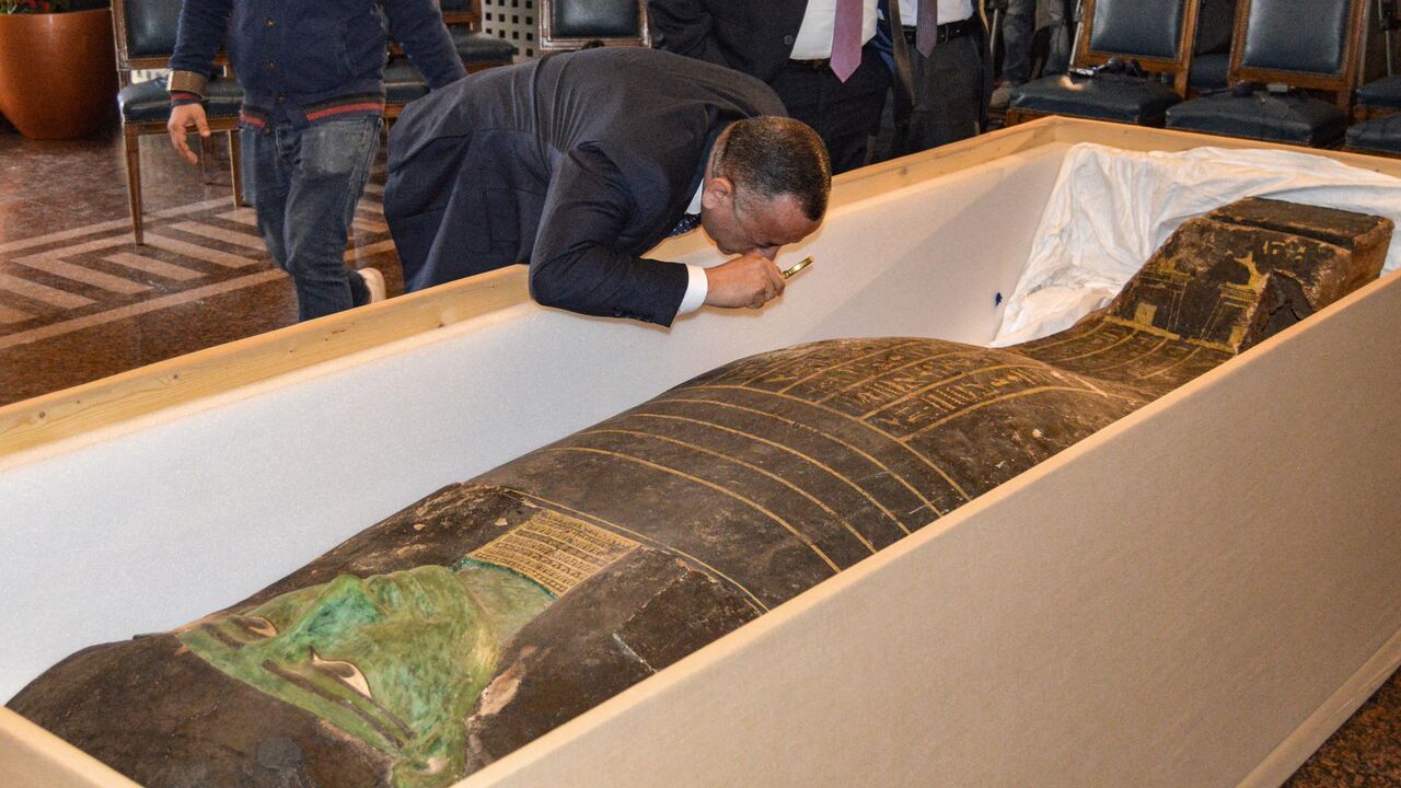 Mostafa Waziri, the head of Egypt's Supreme Council of Antiquities, uses a magnifying glass to inspect an ancient Egyptian wooden sarcophagus being handed over and which was formerly displayed at Houston Museum of Natural Sciences after having been looted and smuggled years prior, at the foreign ministry headquarters in the capital Cairo on January 2, 2023. Photo by -/AFP via Getty Images)