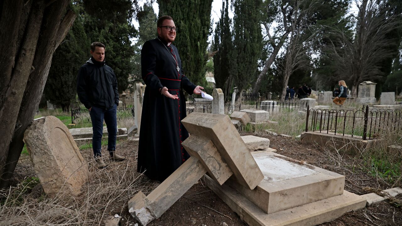 Caretakers of the Protestant cemetery inspect vandalised graves on Mount Zion outside Jerusalem's Old City on January 4, 2023. - (Photo by AHMAD GHARABLI/AFP via Getty Images)