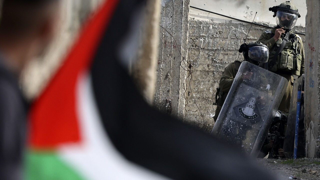 A Palestinian demonstrator waves a national flag during confrontations with Israeli troops, following a protest against the expropriation of Palestinian land by Israel in the occupied West Bank, in the village of Kfar Qaddum, near the Jewish settlement of Kedumim, Jan. 6, 2023.