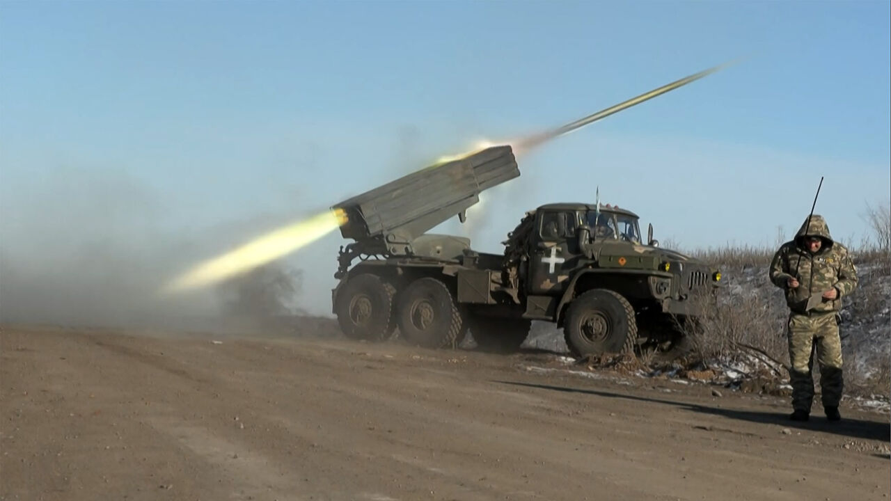 This grab taken from AFP video footage shows a member of Ukraine's military looking away as a rocket launcher fires on the outskirts of Soledar, whose fate was uncertain after Russian Wagner group claimed it controlled the town, Ukraine, Jan. 11, 2023.