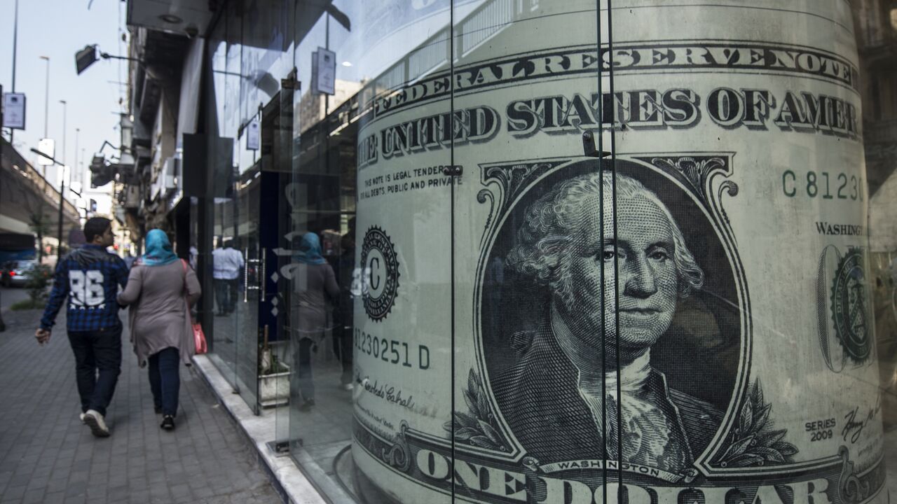 People walk past a currency exchange shop displaying a giant US dollars banknote in downtown Cairo on Nov. 3, 2016. 