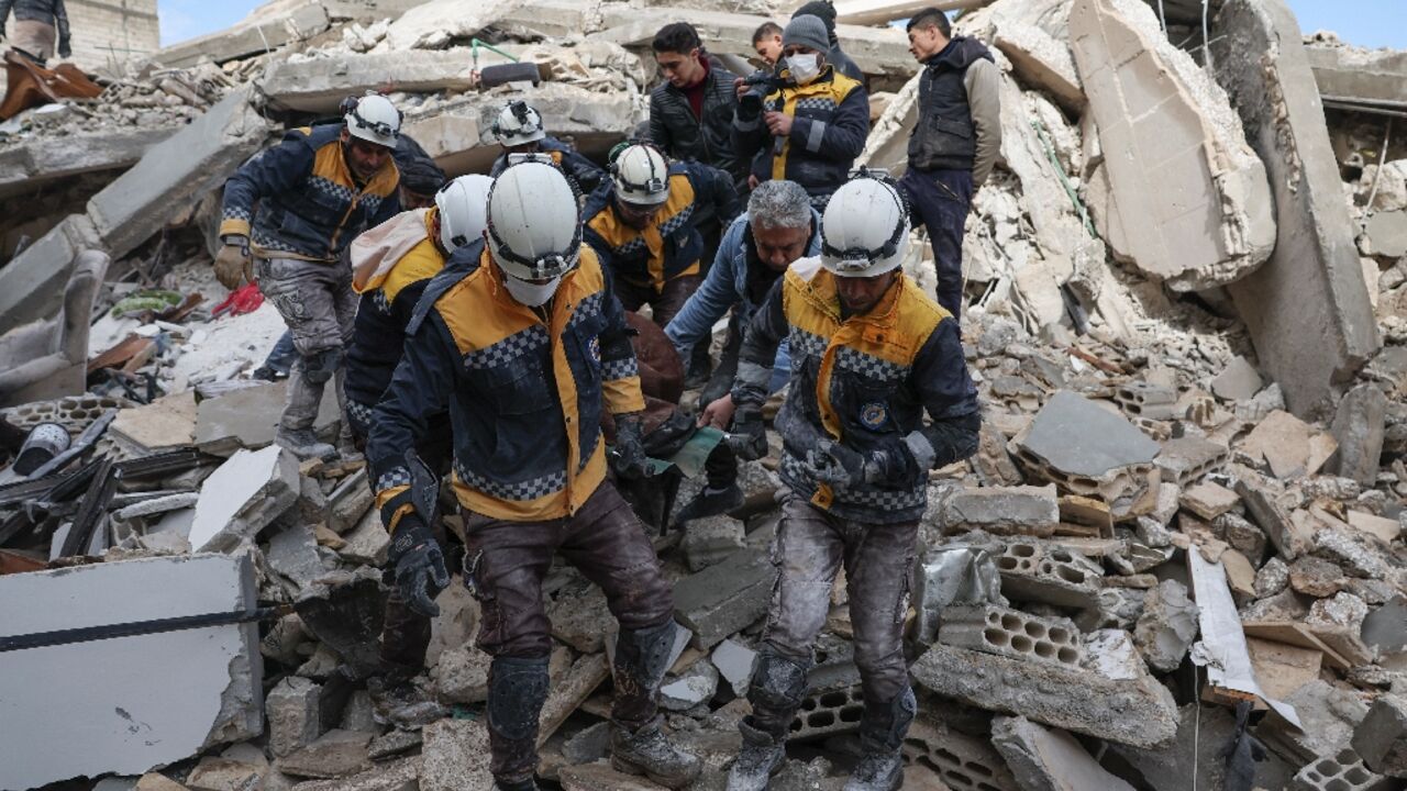 White Helmets rescuers emerge from the rubble with a casualty from the earthquake in the village of Azmarin, in Syria's rebel-held northwestern Idlib province