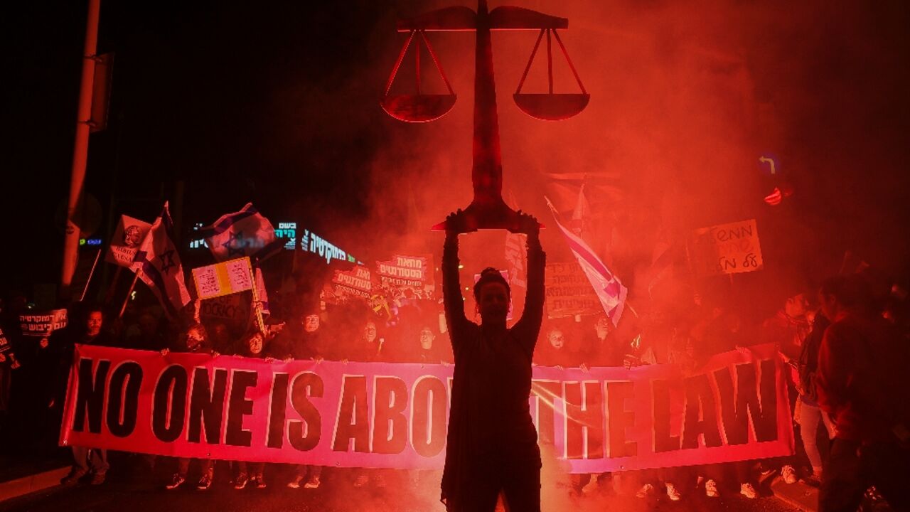 Israeli protesters lift a banner during a rally in central Tel Aviv on February 11 against controversial legal reforms being touted by the country's hard-right government