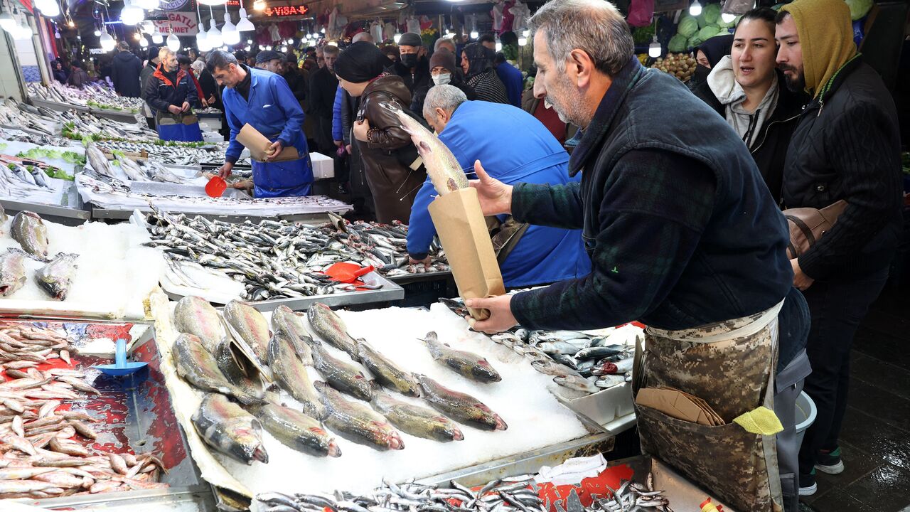 A fisherman sells his fish at a public market where customers shop  in the historical district of Ulus in Ankara on December 30, 2022. (Photo by ADEM ALTAN/AFP via Getty Images)