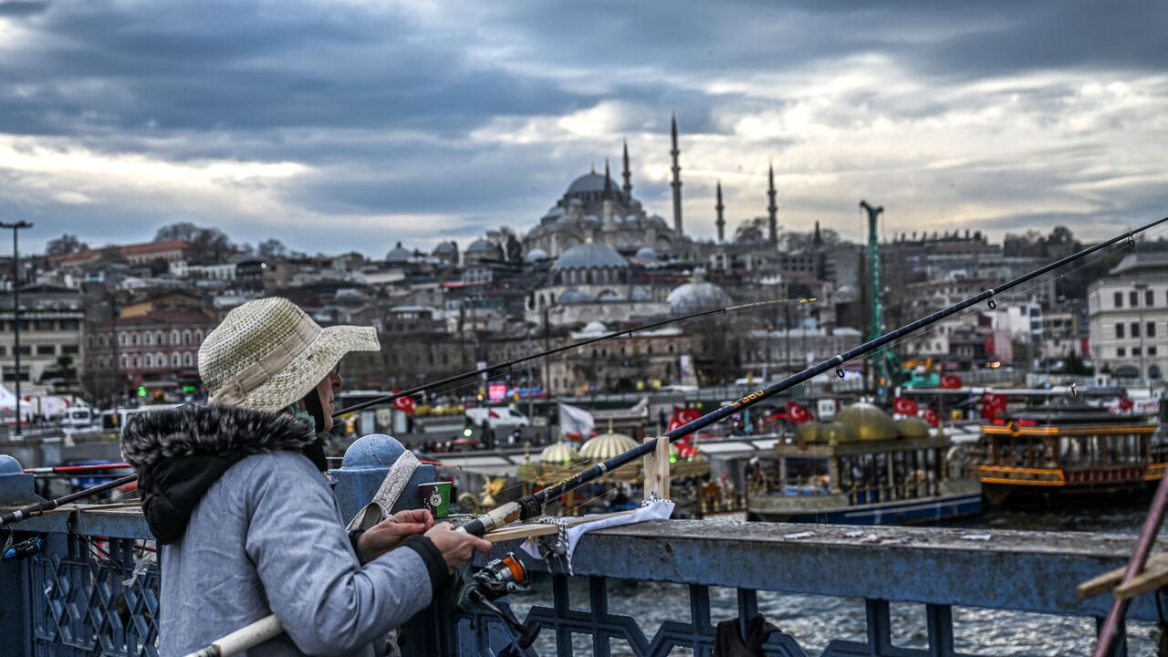 People fish from the Galata bridge, near Suleymaniye mosque (backround) in the Eminonu district of Istanbul, on January 10, 2023. (Photo by OZAN KOSE/AFP via Getty Images)