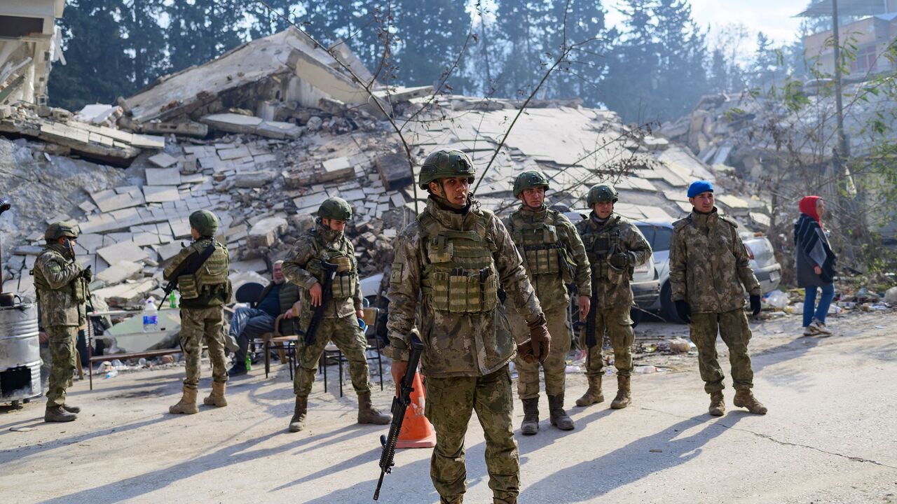 Turkish soldiers stand next to a destroyed building in Hatay.