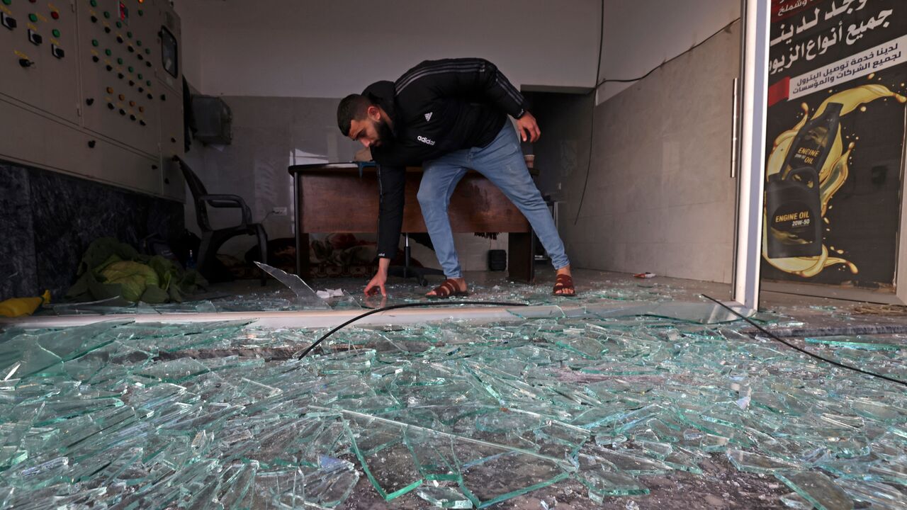 A Palestinian clears debris at a petrol station following Israeli strikes in Gaza City, early on February 13, 2023. - Israel hit Gaza with air strikes in response to a rocket fired from the Palestinian enclave at the weekend, the army said, as unrest persisted in the occupied West Bank. (Photo by MOHAMMED ABED/AFP via Getty Images)