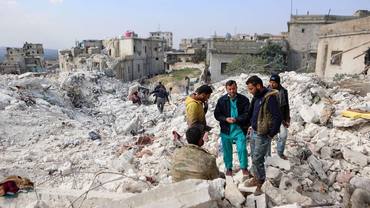 Nurse anaesthetist Abdelbaset Khalil (2nd L) stands with others on the rubble of his house following a deadly earthquake, near the hospital in the town of Harim, in Syria's rebel-held northwestern Idlib province at the border with Turkey, on February 11, 2023. - Following the 7.8-magnitude earthquake rocked Turkey and Syria on February 6, toppling hundreds of buildings and leaving a death toll of at least 3,581 in Syria, supplies have been slow to arrive in the war-torn country where years of conflict have