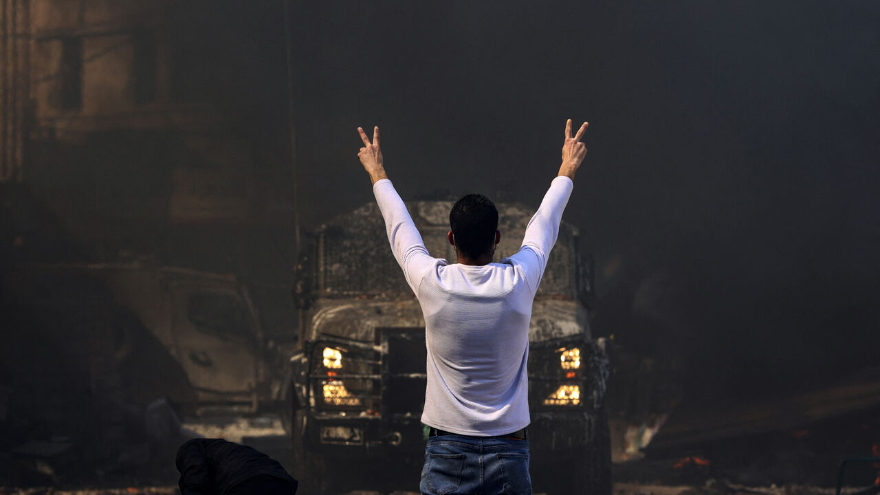 A Palestinian man flashes the victory sign as he faces an Israeli military vehicle, during a raid on the occupied-West Bank city of Nablus, on February 22, 2023. - Israeli troops killed at least 10 Palestinians in a raid on Nablus, while more than 80 suffered gunshot wounds, the Palestinian health ministry said. (Photo by ZAIN JAAFAR/AFP via Getty Images)