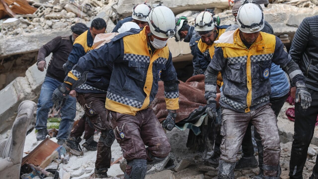 Members of the Syrian Civil Defense, or White Helmets, carry a quake victim from the rubble