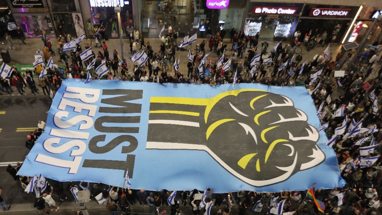 Israelis in Tel Aviv carry a sign during their latest weekly protest against the government's judicial reforms