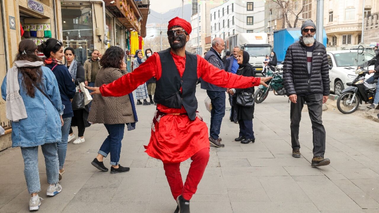 An Iranian man dressed as the fictional folklore character Hajji Firuz performs on at a street in Tehran ahead of the Nowruz New Year festival