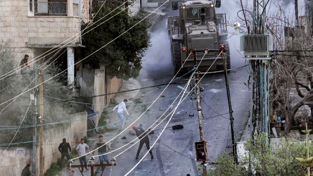 Young Palestinians confront a military vehicle during an Israeli raid on Jenin refugee camp in the occupied West Bank which killed six people on Tuesday