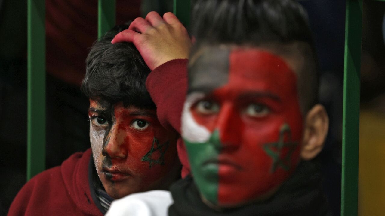 Palestinian football fans in Gaza watch Morocco's team play during the 2022 World Cup on December 14, 2022, with their faces painted in the Moroccan and Palestinian flags