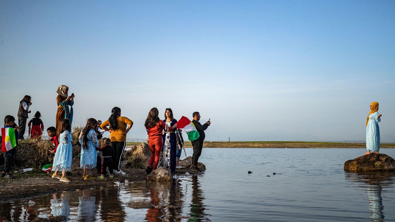 A woman dressed in traditional clothing poses for a picture while standing on a rock in the Mazqaft water reservoir in the countryside of the town of Qahtaniyah in Syria's northeastern Hasakah province close to the border with Turkey, during Syrian Kurdish celebrations on the second day of Nowruz, the Persian New Year, on March 21, 2021. (Photo by DELIL SOULEIMAN/AFP via Getty Images)