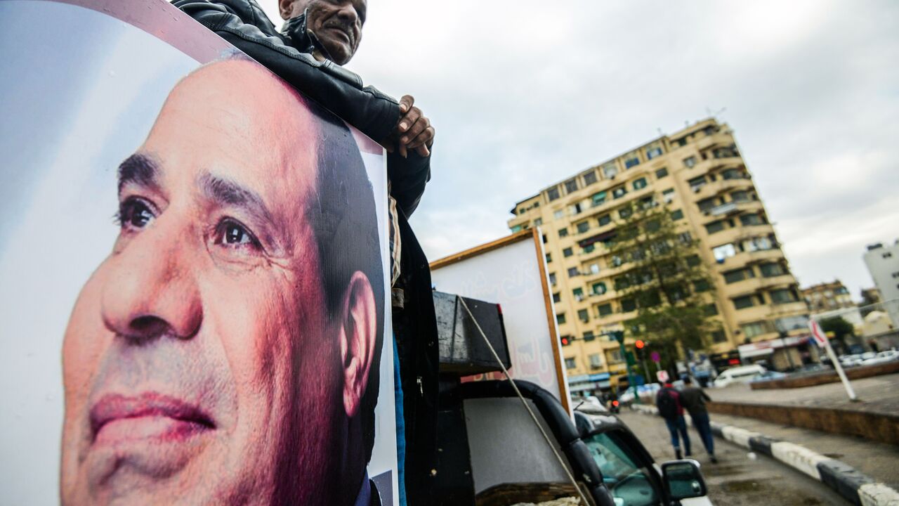 A supporter of Egyptian President Abdel Fattah al-Sisi stands in the back of a pickup truck bearing his portrait and loudspeakers, in the capital Cairo's Tahrir square on January 25, 2018, as the country marks the seventh anniversary of the 2011 uprising that ended the 30-year reign of former President Hosni Mubarak. / AFP PHOTO / MOHAMED EL-SHAHED (Photo credit should read MOHAMED EL-SHAHED/AFP via Getty Images)