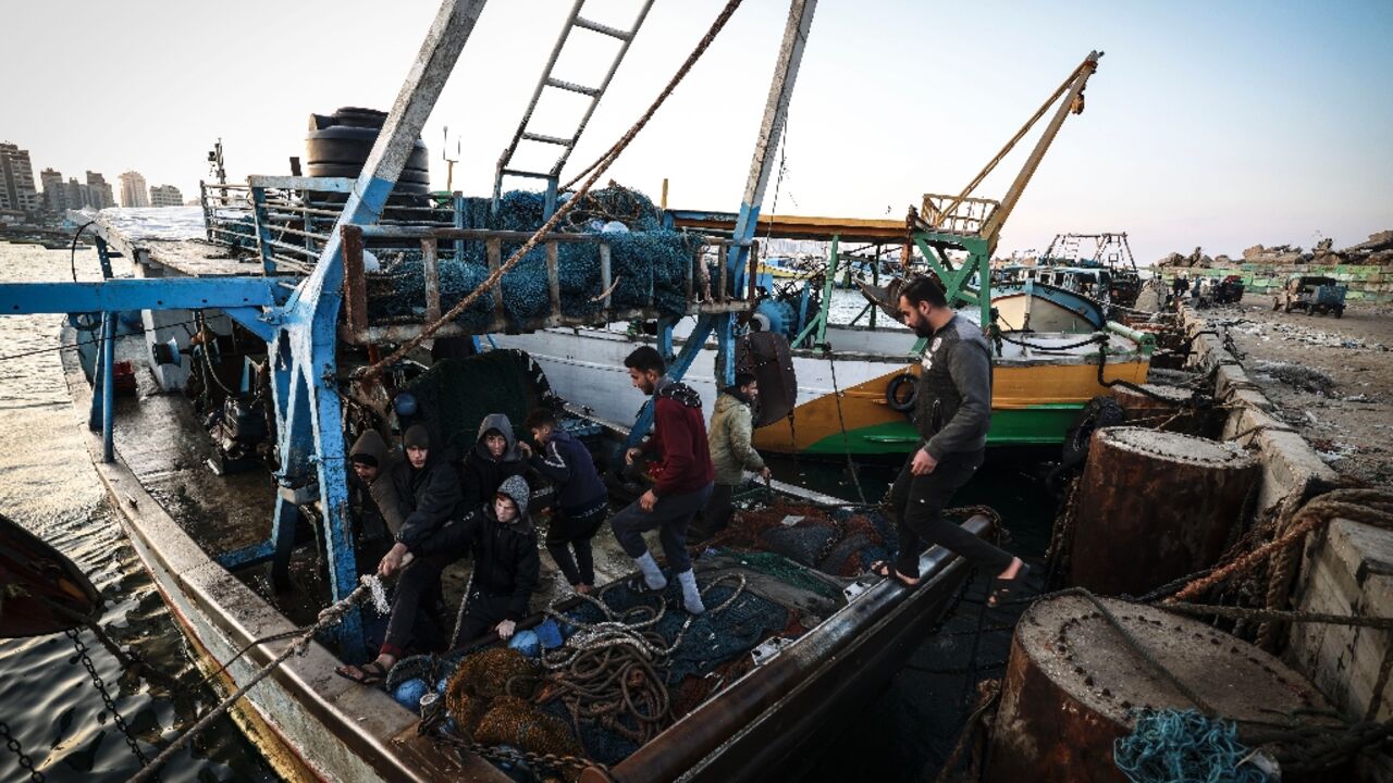 Palestinian fisherman Jihad al-Hissi and his sons aboard their boat at the seaport in Gaza City 