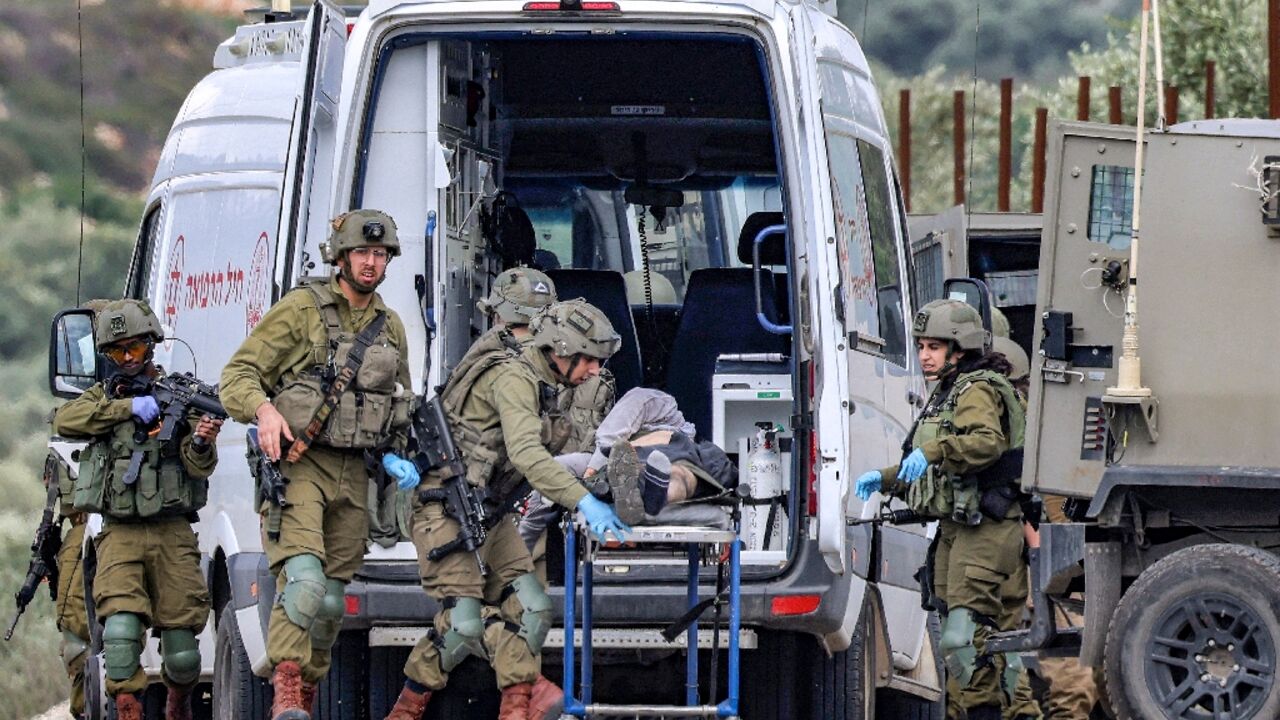 Israeli soldiers pass an ambulance with the body of a Palestinian militant killed during what the army called an exchange of fire near Elon Moreh settlement in the occupied West Bank