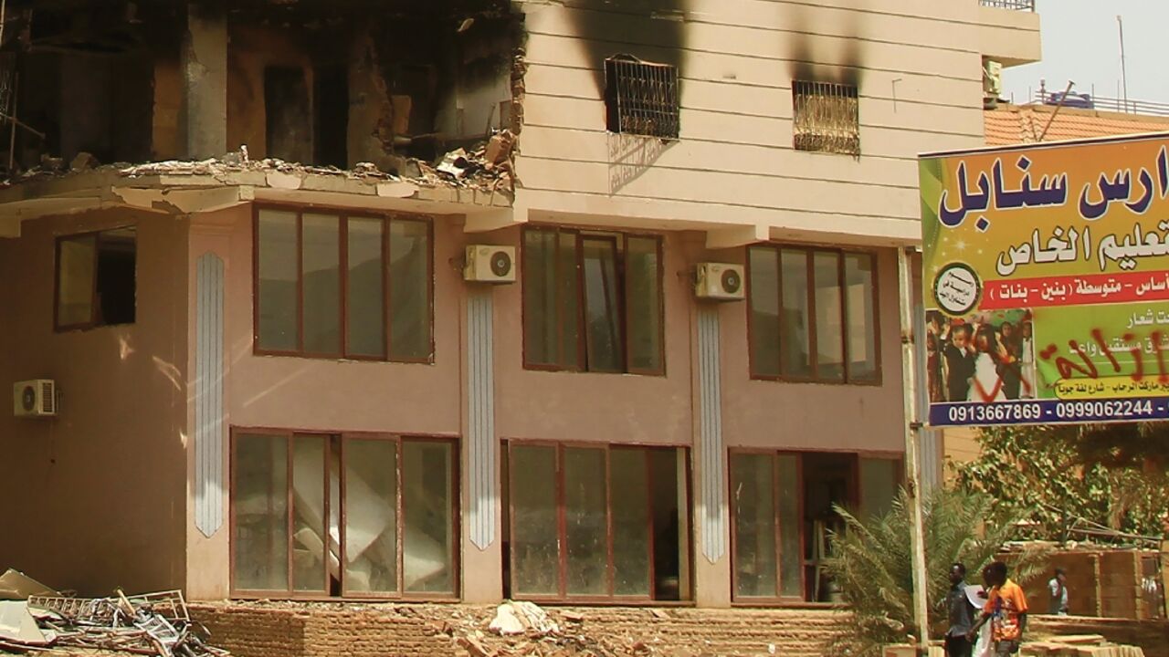 Men walk past a building damaged during battles between the forces of two rival Sudanese generals in the southern part of Khartoum, on April 23, 2023