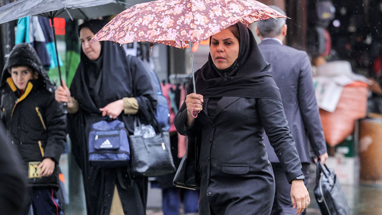 A woman walks with an umbrella at Enghelab Square in Iran's capital Tehran on December 5, 2022. (Photo by ATTA KENARE / AFP) (Photo by ATTA KENARE/AFP via Getty Images)