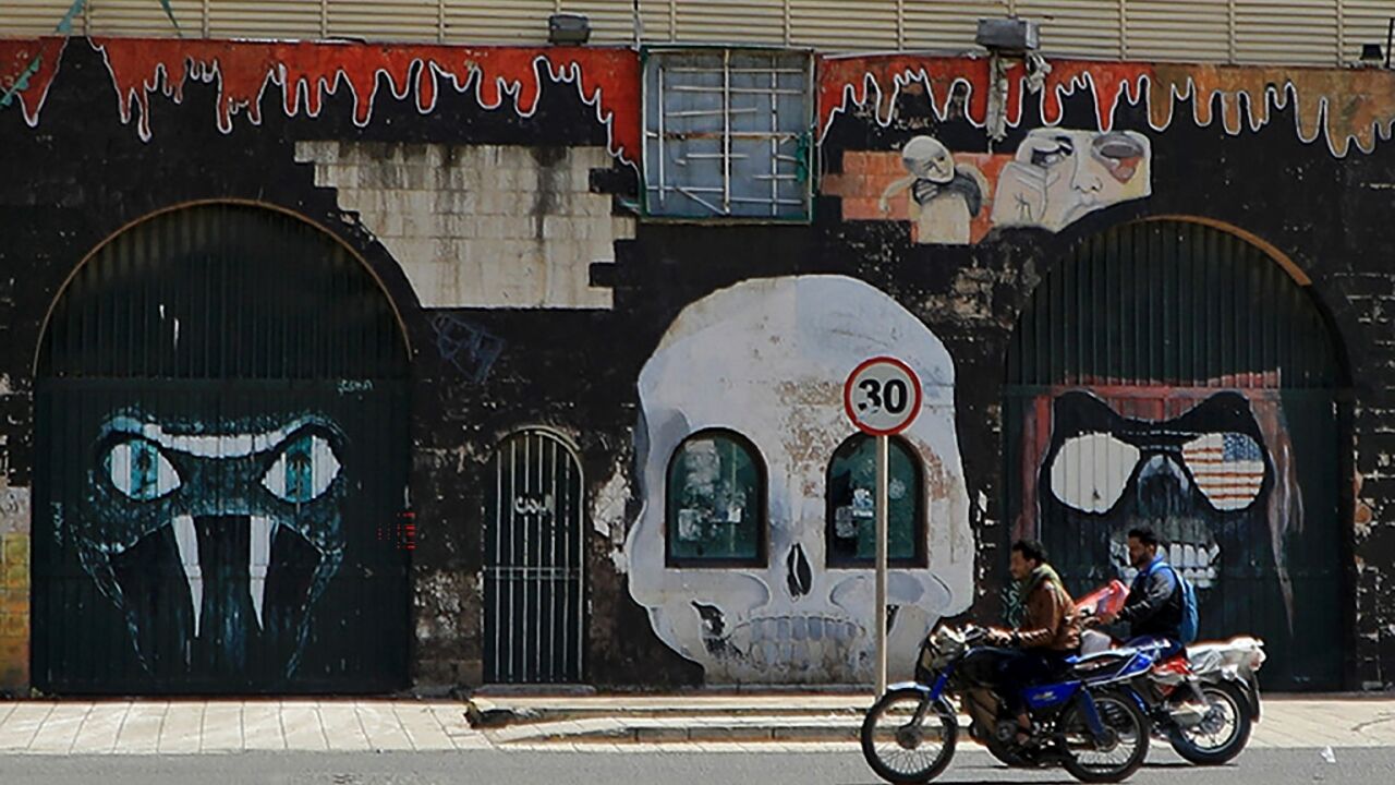 Motorcyclists drive past the closed Saudi embassy in Sanaa