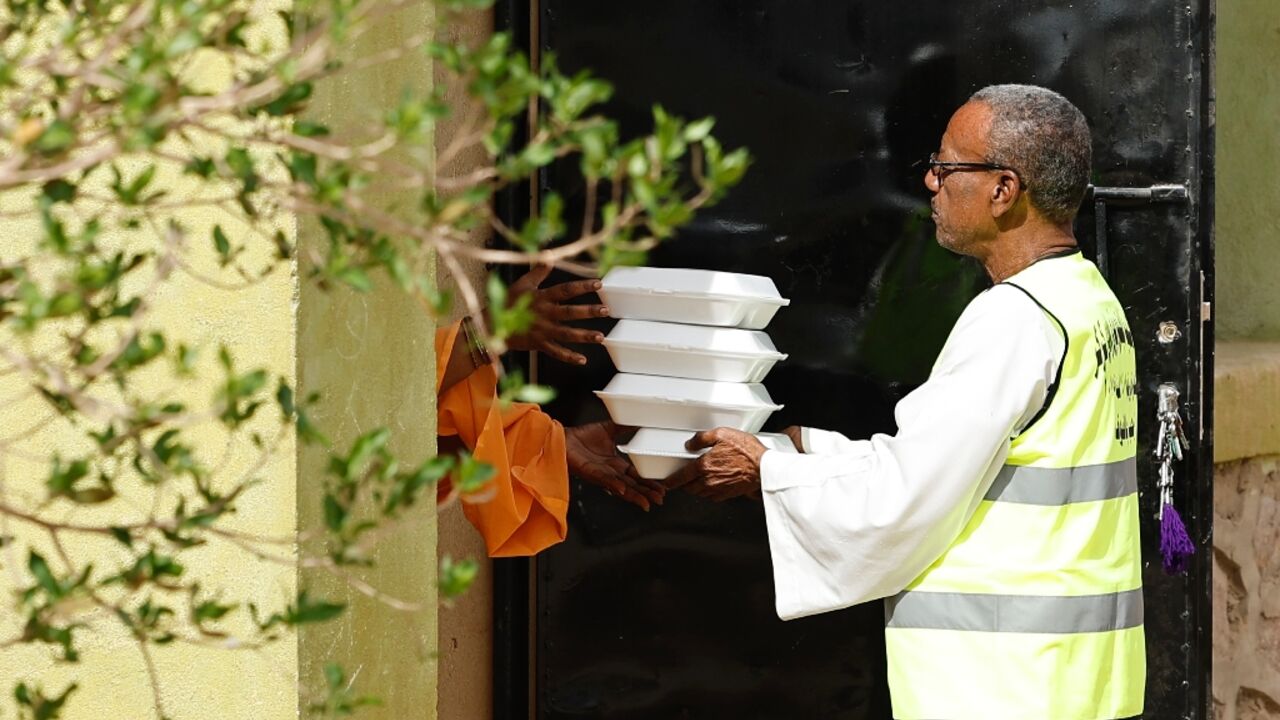 An Egyptian volunteer delivers free meals to a family of Sudanese refugees hosted at an Egyptian home in the village of Wadi Karkar near Aswan 