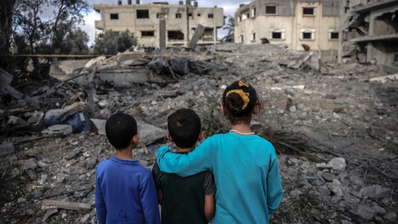 Children stand amidst the rubble of a building hit by an Israeli air strike in Deir al-Balah in the centre of the Gaza Strip