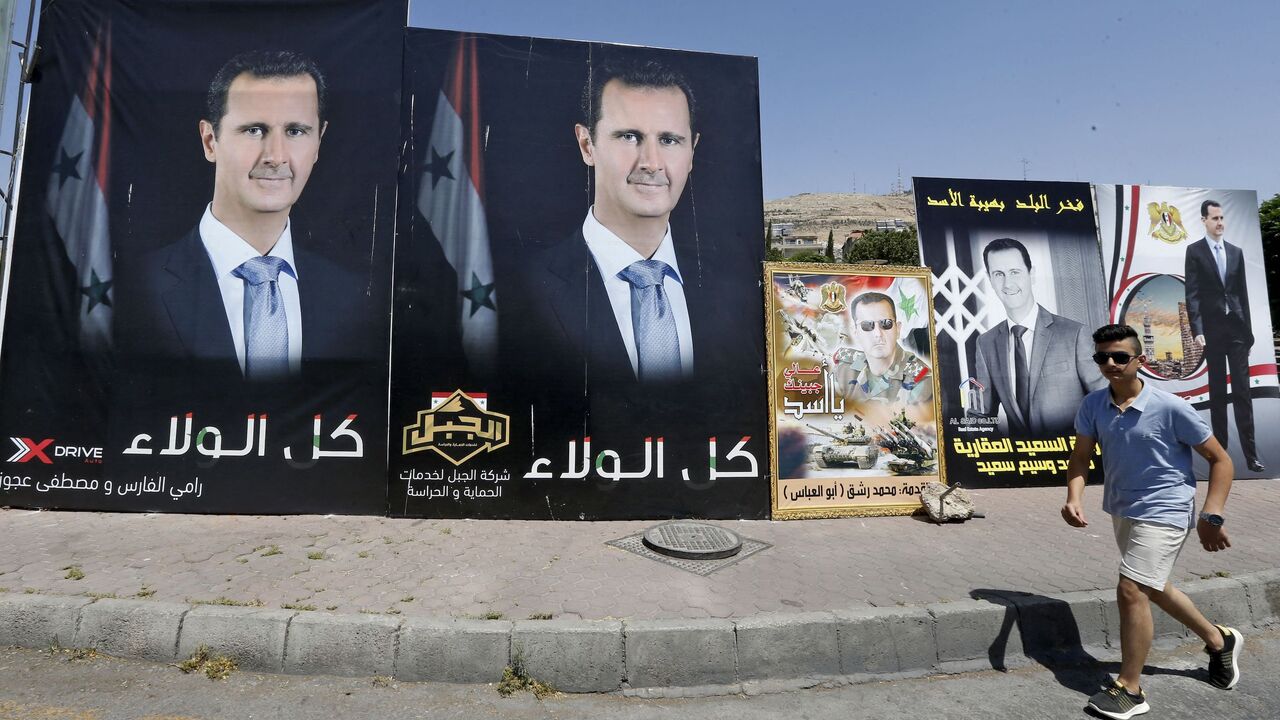 A man walks past a poster of President Bashar al-Assad, a candidate for the Presidential election, in the Syrian capital Damascus on May 17, 2021. - A Syrian former minister and a member of the Damascus-tolerated opposition will face Bashar al-Assad in this month's presidential election, the constitutional court said. The Assad-appointed body approved only three out of 51 applications to stand in the May 26 ballot, among them the 55-year-old president himself, widely expected to win a fourth mandate. (Photo