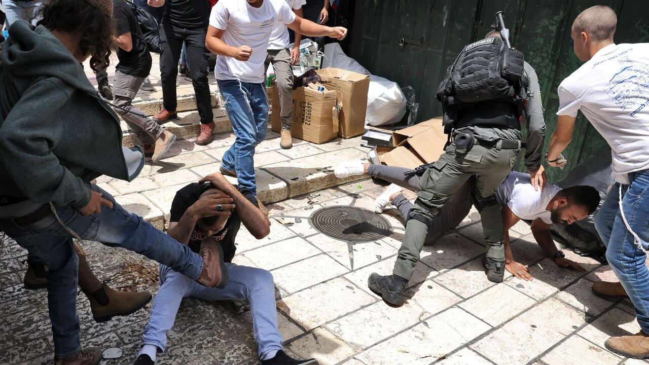 An Israeli border guard intervenes as participants of an Israeli annual far-right, flag-waving rally, beat Palestinian men during the event in the Old City of Jerusalem, on May 18, 2023. Jerusalem police and residents were bracing for extremist ministers and their supporters to rally today in an annual flag-waving march commemorating Israel's capture of the Old City. Following the 1967 Six-Day War, Israel annexed east Jerusalem and its Old City in a move never recognised by the international community. (Pho