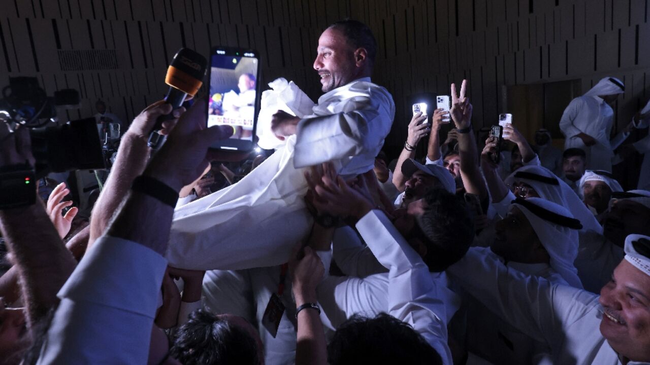 Kuwait's former parliament speaker Marzouq al-Ghanim celebrates with supporters after he retains his seat in a general election that returned an opposition majority