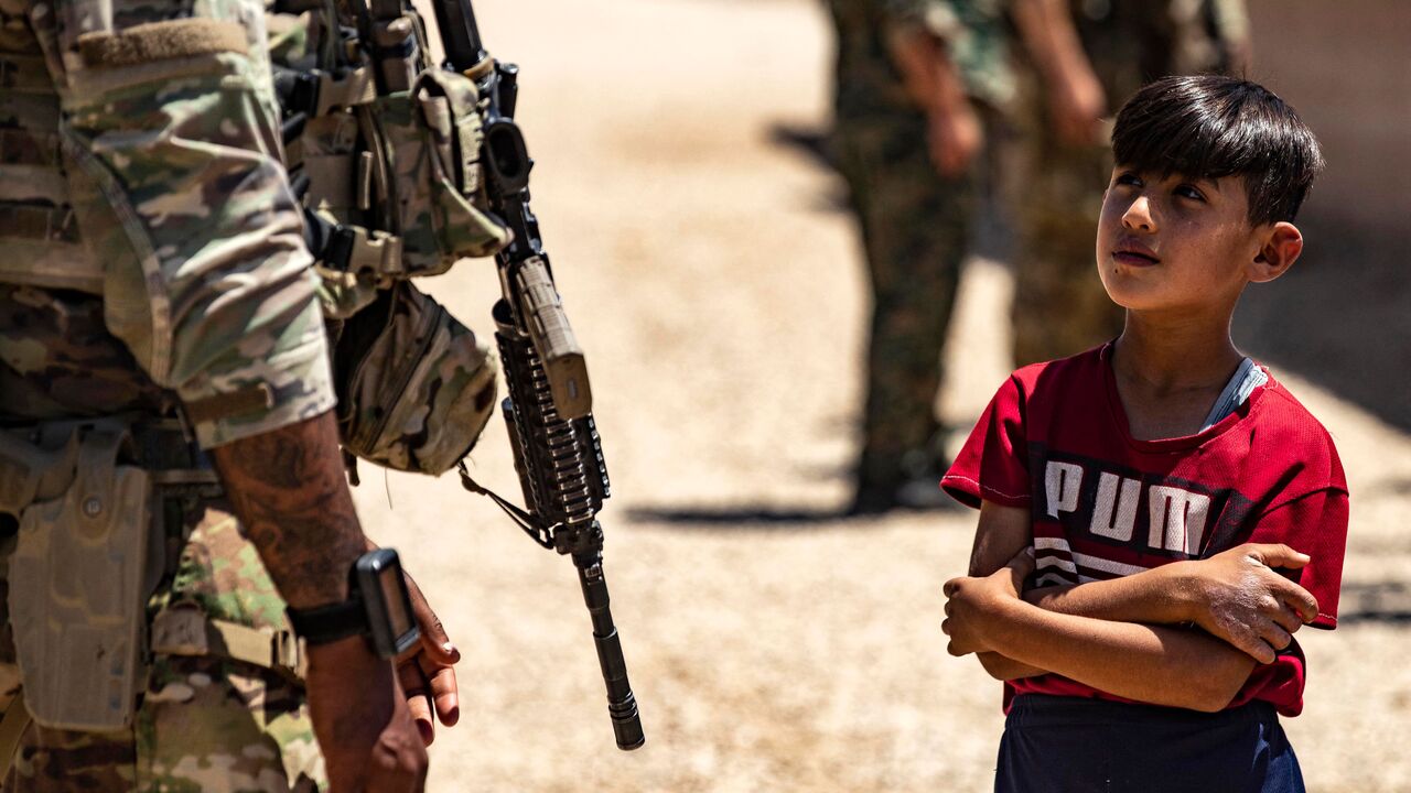 A child stares at a US soldiers patrolling a village in the countryside of the Kurdish-majority city of Qamishli in Syria's northeastern Hasakeh province, near the Turkish border, on July 23, 2022. (Photo by Delil SOULEIMAN / AFP) (Photo by DELIL SOULEIMAN/AFP via Getty Images)