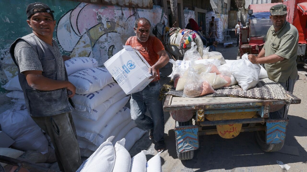 Palestinians carry bags of flour provided as aid to poor families from the United Nations Relief and Works Agency for Palestine Refugees (UNRWA) distribution center, at Al-Shati refugee camp in Gaza city Palestinians carry bags of flour provided as aid to poor families from the United Nations Relief and Works Agency for Palestine Refugees (UNRWA) distribution center, at Al-Shati refugee camp in Gaza city