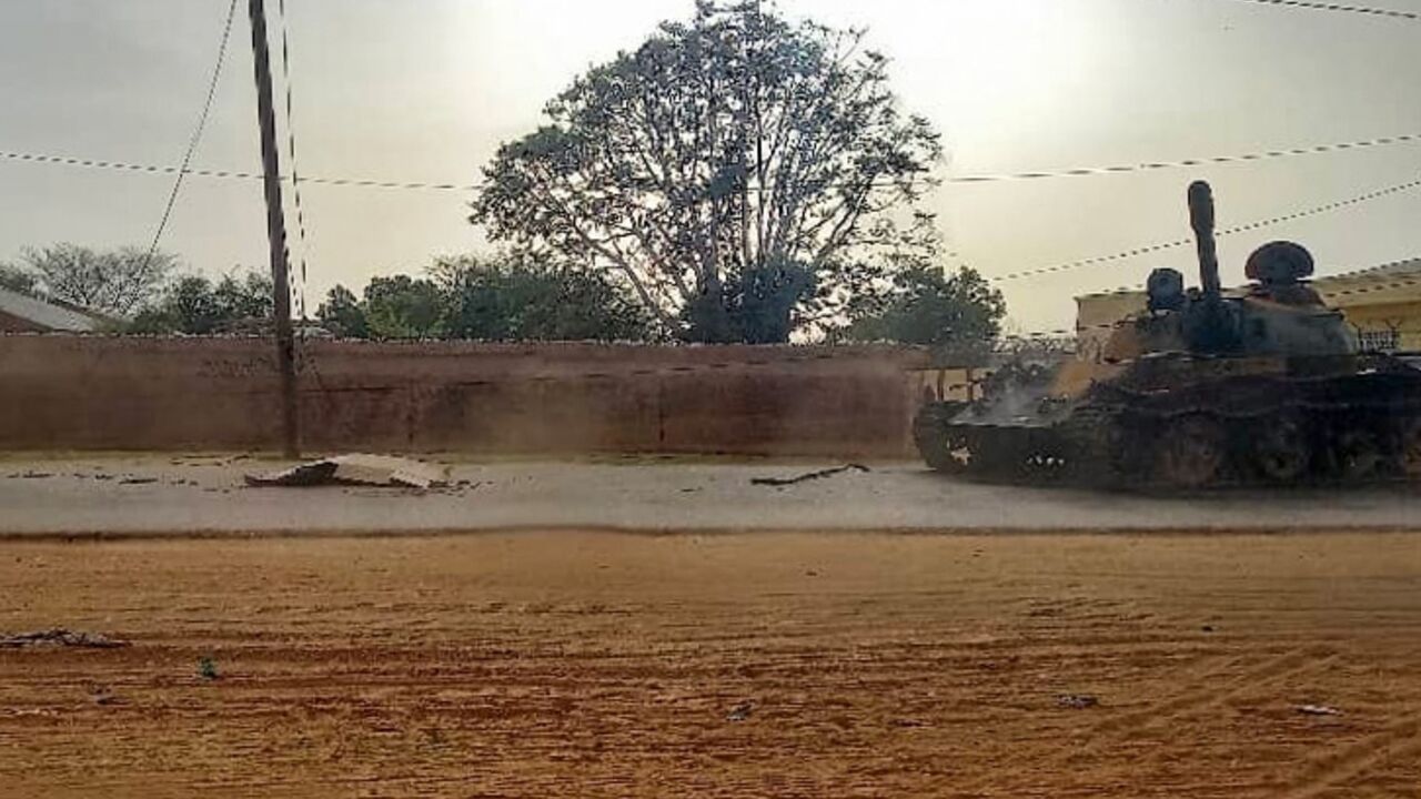 A covered body lies across from a miliatry armoured vehicle on a street in the West Darfur state capital El Geneina