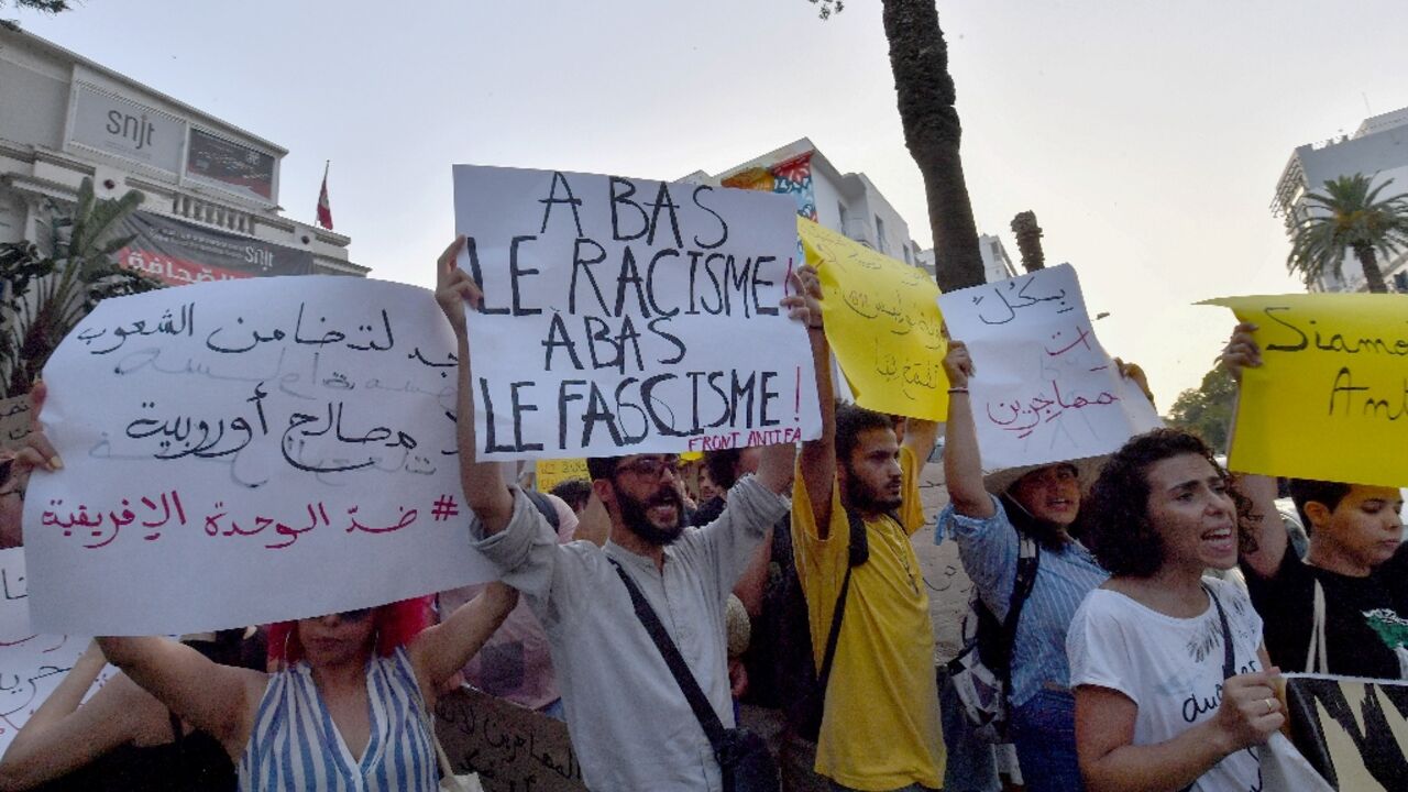 Demonstrators lift placards and chant anti-racism slogans during a protest in Tunis in support of migrants Demonstrators lift placards and chant anti-racism slogans during a protest in Tunis in support of migrants