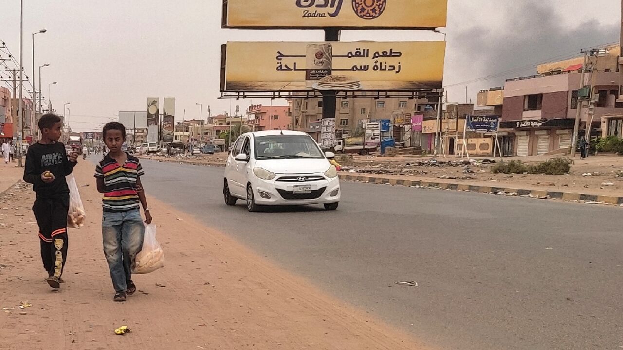 Smoke rises from nearby fighting as children take bags of bread home in Omdurman Smoke rises from nearby fighting as children take bags of bread home in Omdurman