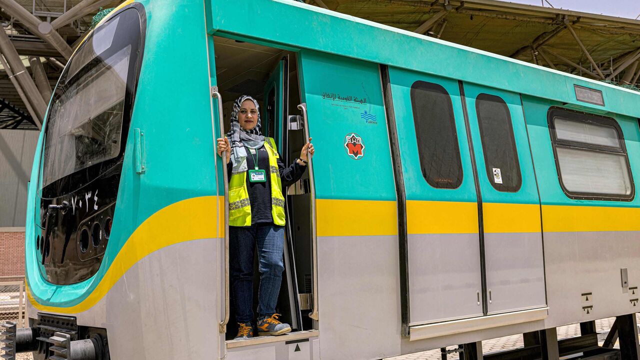 Hind Omar, an Egyptian woman metro train driver, poses through the entrance of a life-size train simulator at Adly Mansour station in the capital Cairo's northeastern neighbourhood of Heliopolis on May 31, 2022. - As it prepares to expand to serve a population now exceeding 20 million, the Cairo metro has recruited Egypt's first female train drivers, a novelty in a country where few women have formal jobs. Since April, commuters on the network's newest line have seen women take the controls in the driver's