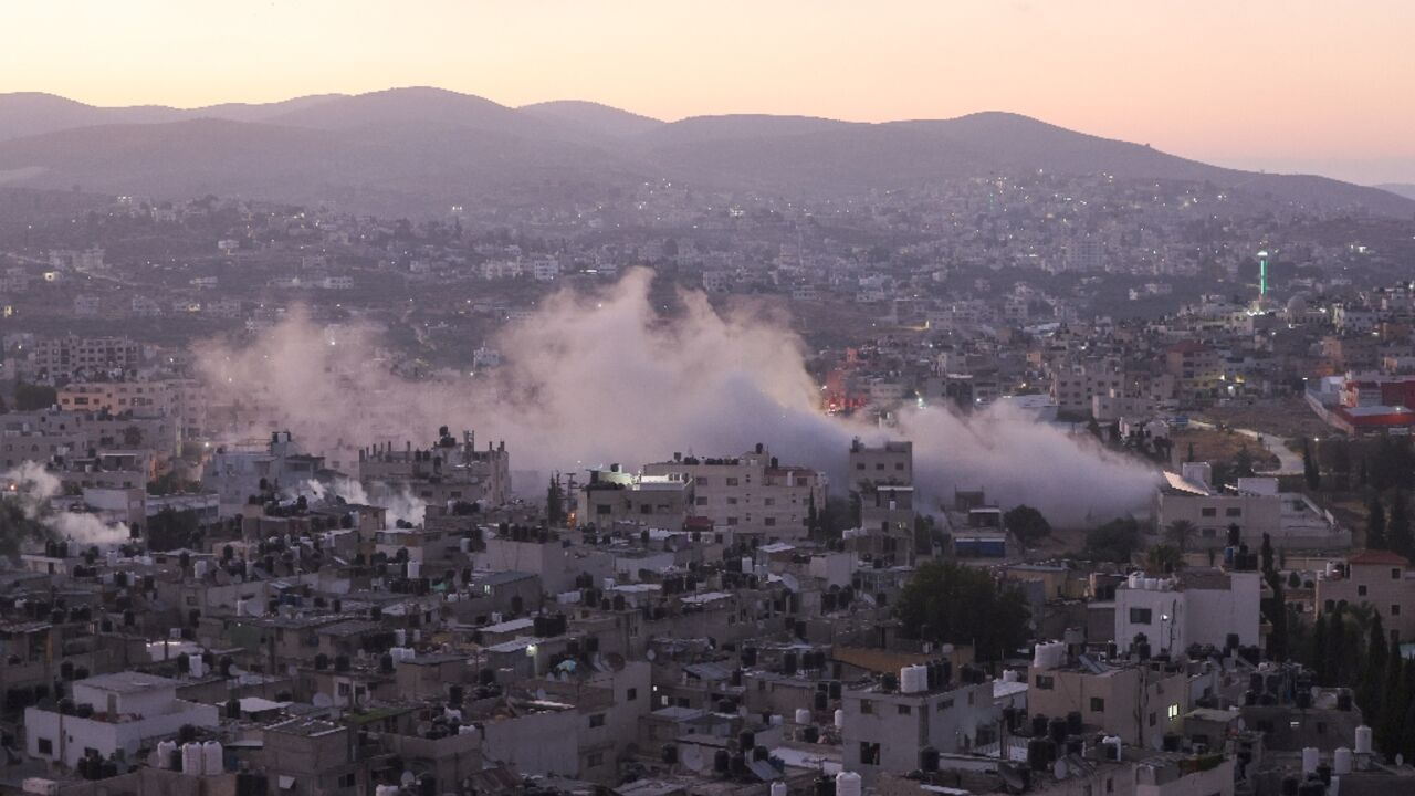 Smoke billows as Israeli soldiers demolish a house at the Askar camp for Palestinian refugees east of Nablus city in the occupied West Bank