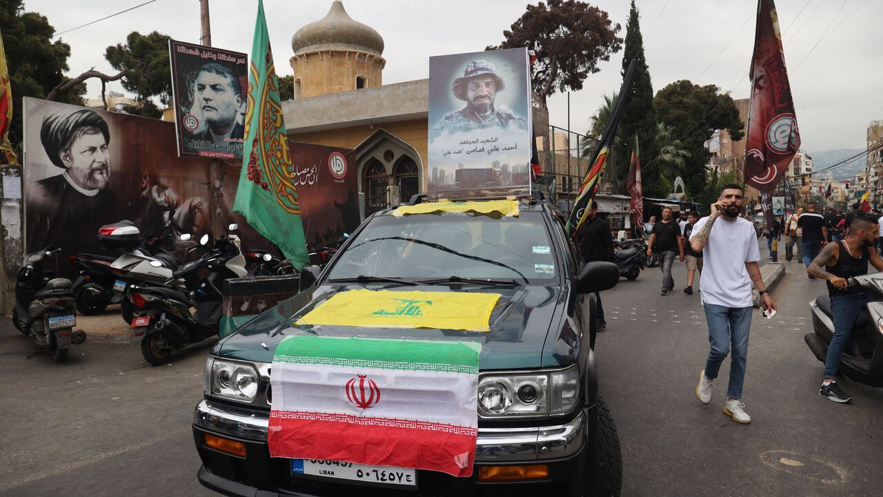 A vehicle displays the flags of Iran and the Lebanese Shiite movement Hezbollah as it moves in a funerary procession for a fallen fighter in Beirut's predominantly-Shiite Muslim southern suburb, on August 10, 2023 after he was killed the previous day amidst clashes between Hezbollah and residents of the Christian town of Kahale in Mount Lebanon. The Lebanese army said on August 10 that it had seized munitions from a Hezbollah truck that overturned near Beirut, leading to deadly clashes between Christian res