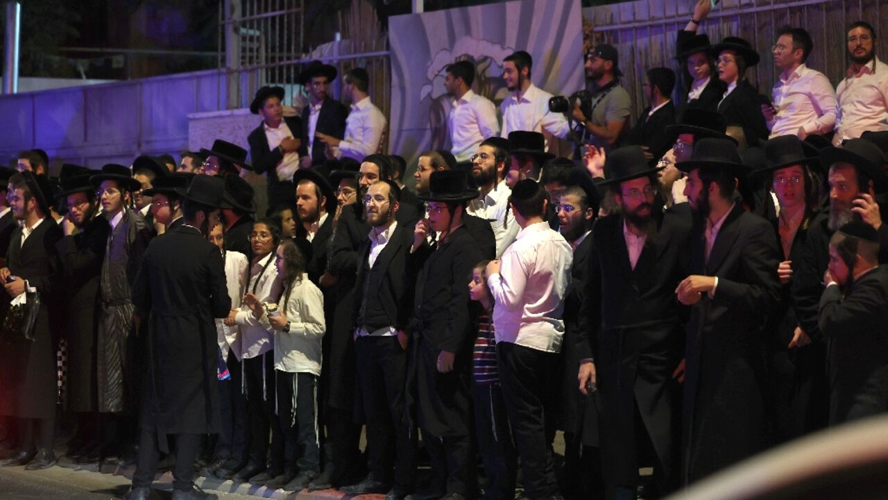 Ultra-Orthodox Jewish bystanders watch emergency and security personnel at the scene of the attack