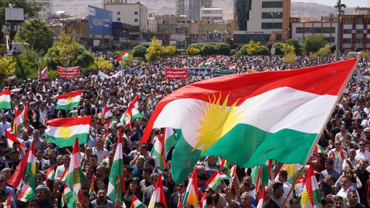 People in Dohuk city lift the regional flag during a rally over unpaid salaries in the autonomous Kurdish region of northern Iraq