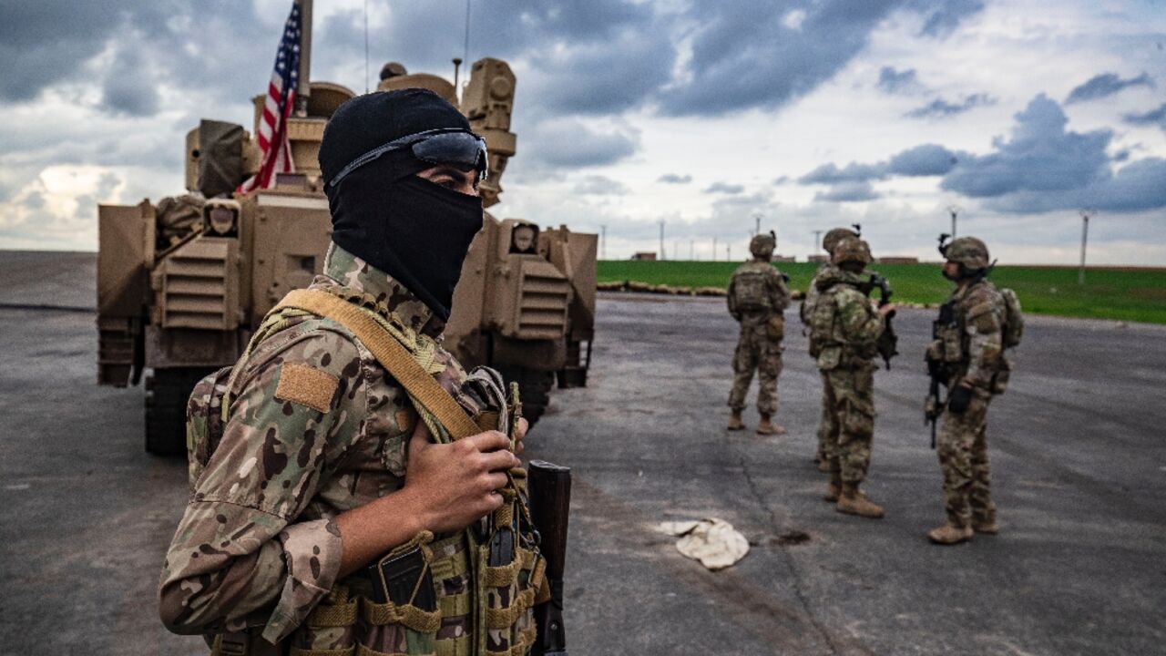 A member of the Syrian Democratic Forces and US soldiers are pictured on the outskirts of Rumaylan in Syria's northeastern Hasakeh province, bordering Turkey, on March 27, 2023