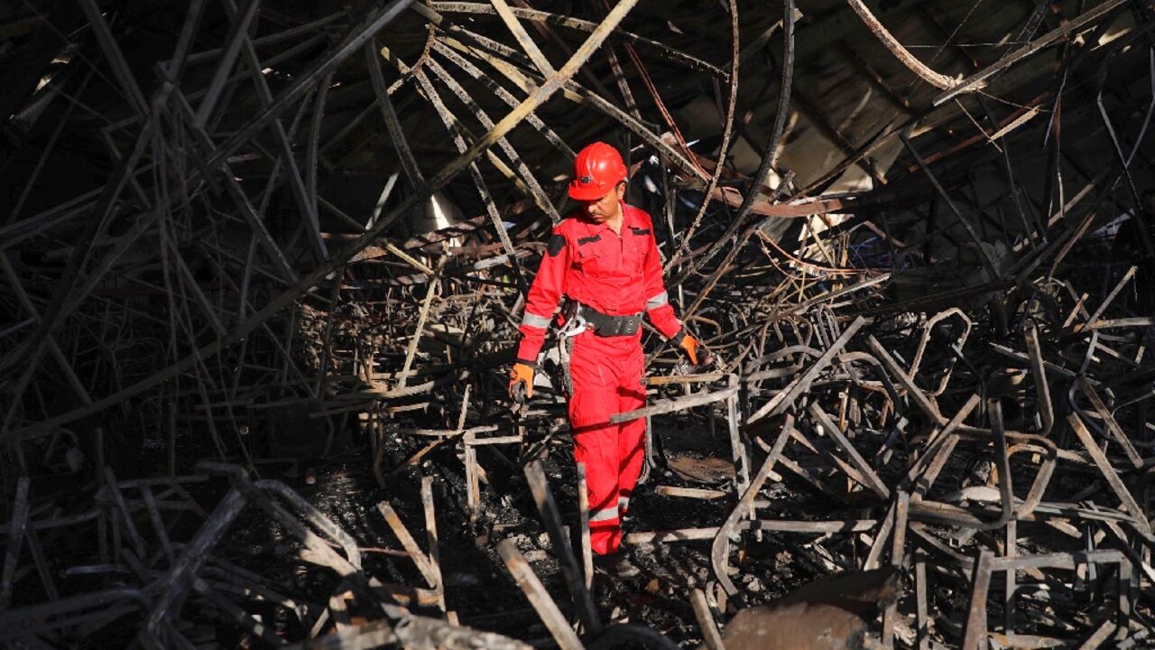 A firefighter surveys the charred and mangled interior of the reception hall where hundreds of Iraqis had been celebrating a wedding