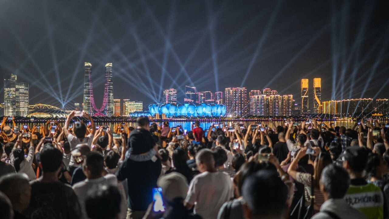 People watch a light show of the Hangzhou Olympic Sports Centre Stadium