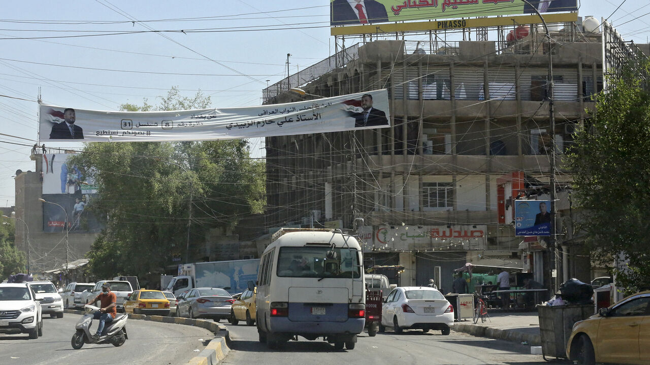 Iraqis drive past electoral billboards and placards of candidates for the upcoming parliamentary elections in Karrada district, Baghdad, Iraq, Sept. 19, 2021.