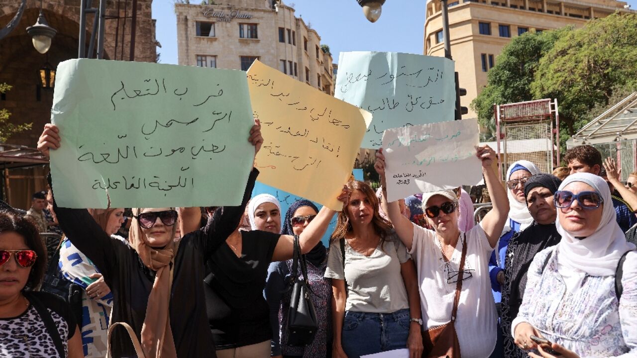 School teachers lift placards during a sit-in outside Lebanon's parliament protesting poor pay at public schools