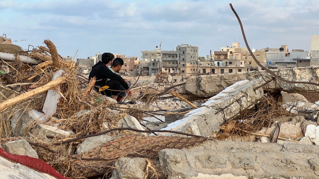 People sit among the rubble in Libya's eastern city of Derna