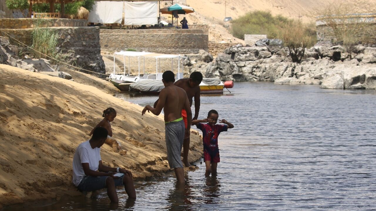 Sudanese who fled the war in their country cool off on the banks of the Nile river in the Egyptian city of Aswan